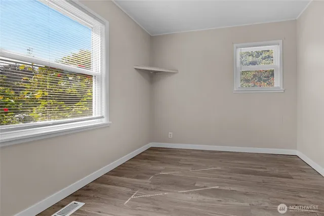a view of an empty room with wooden floor and a window