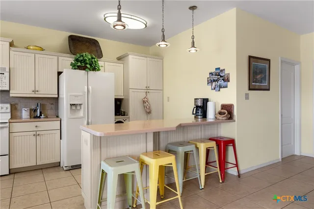 a kitchen with stainless steel appliances kitchen island granite countertop a table chairs and a refrigerator