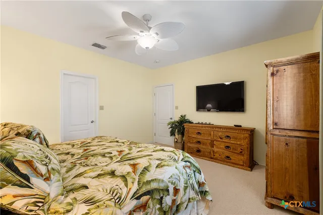 a bedroom with a bed and flat tv screen on dresser