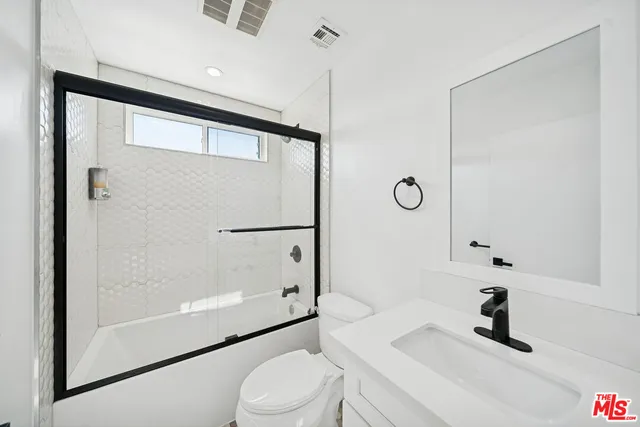 a bathroom with a sink a toilet a mirror and shower