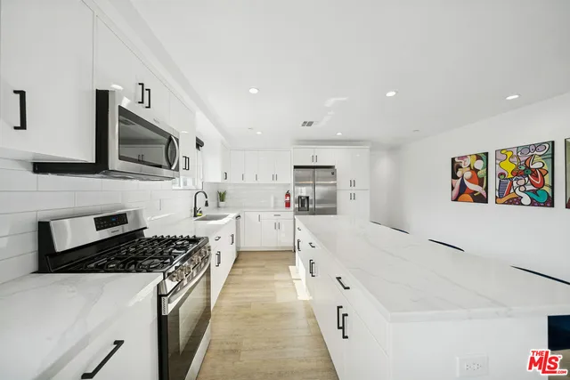 a large white kitchen with stainless steel appliances