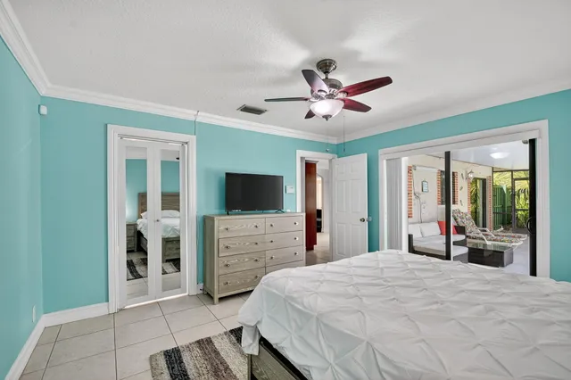 a bedroom with a bed a mirror and a flat tv screen on dresser