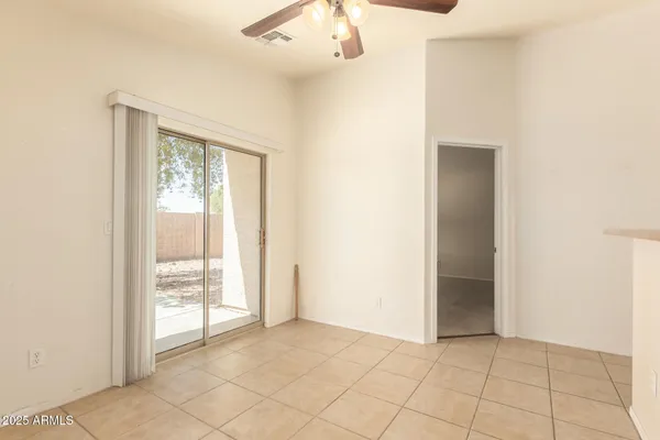 an empty room with chandelier fan and windows