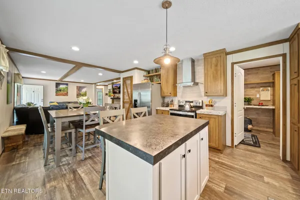 a dining room with stainless steel appliances furniture a window and kitchen view