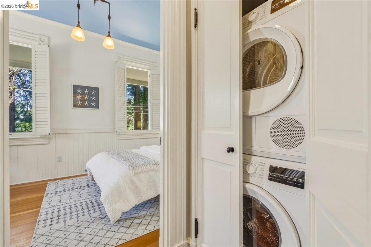 1631 La Vereda Road Berkeley, CA 94709 - Photo 18 of 42 In-unit stacked washer and dryer, hardwood flooring, beadboard wainscoting, and white window shutters