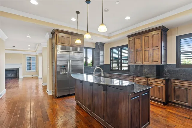 a kitchen with stainless steel appliances granite countertop a sink a stove and wooden floors