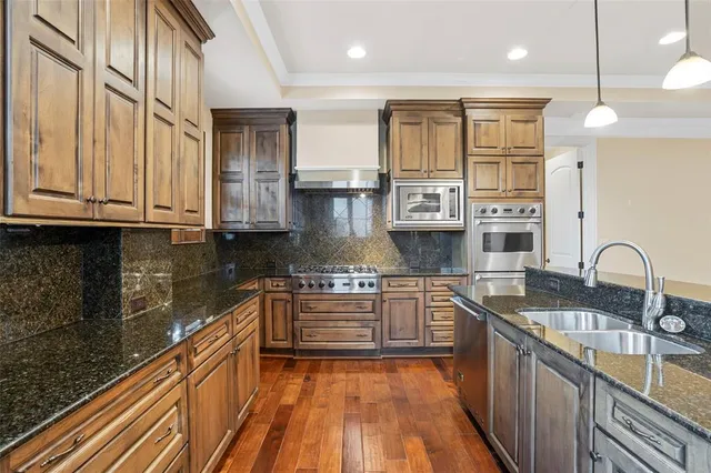 a kitchen with stainless steel appliances granite countertop a sink and wooden cabinets