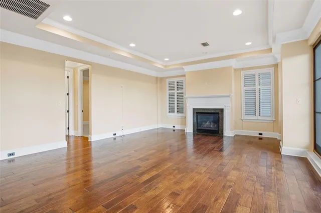 a view of an empty room with wooden floor fireplace and a window