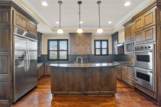 a kitchen with stainless steel appliances granite countertop a stove a sink and a refrigerator