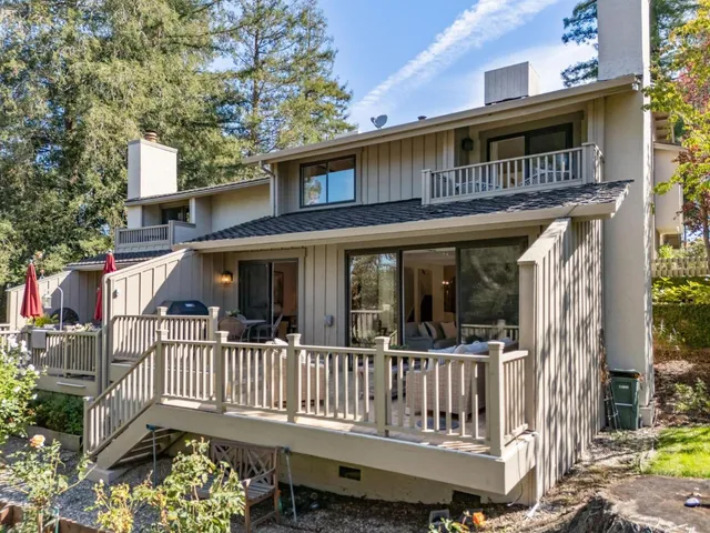 a view of a house with a wooden deck and furniture