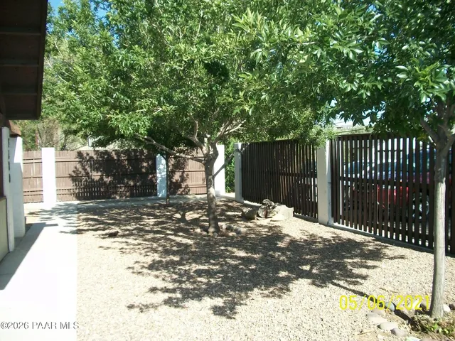 a view of a backyard with wooden fence and large trees