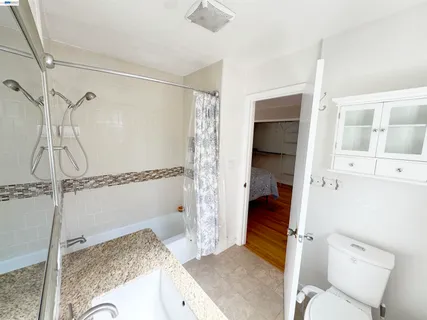 a bathroom with a granite countertop sink and a shower