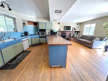 a large kitchen with stainless steel appliances granite countertop a lot of counter space and wooden floors