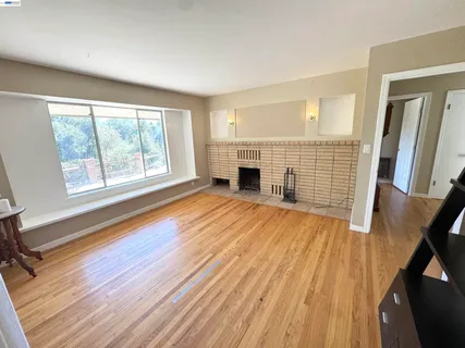 a view of empty room with wooden floor and fireplace