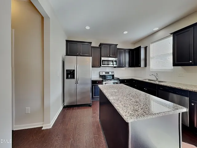 a kitchen with kitchen island granite countertop stainless steel appliances cabinets a sink and a counter space
