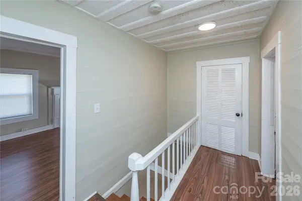 a view of a hallway with wooden floor and closet
