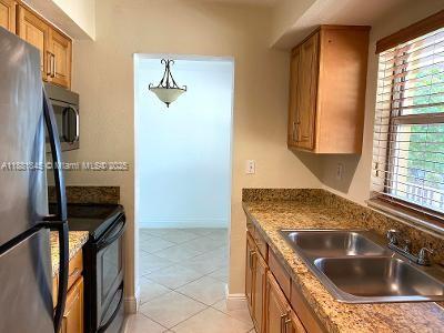 8601 Southwest 94th Street, Unit 227W Miami, FL 33156 - Photo 6 of 17 a kitchen with a sink stove and refrigerator