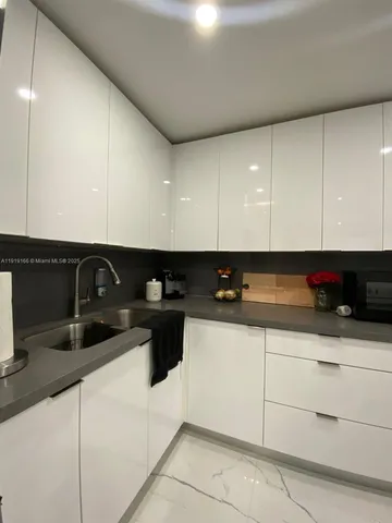 a kitchen with granite countertop white cabinets and black appliances