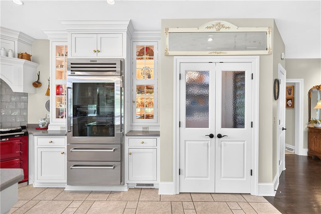 486 Settler Road Ligonier, PA 15658 - Photo 13 of 49 Ceramic floors, Subzero fridge (2024) lighted glass cabinets on both sides, and THE MOST AMAZING PANTRY behind these double glass doors.