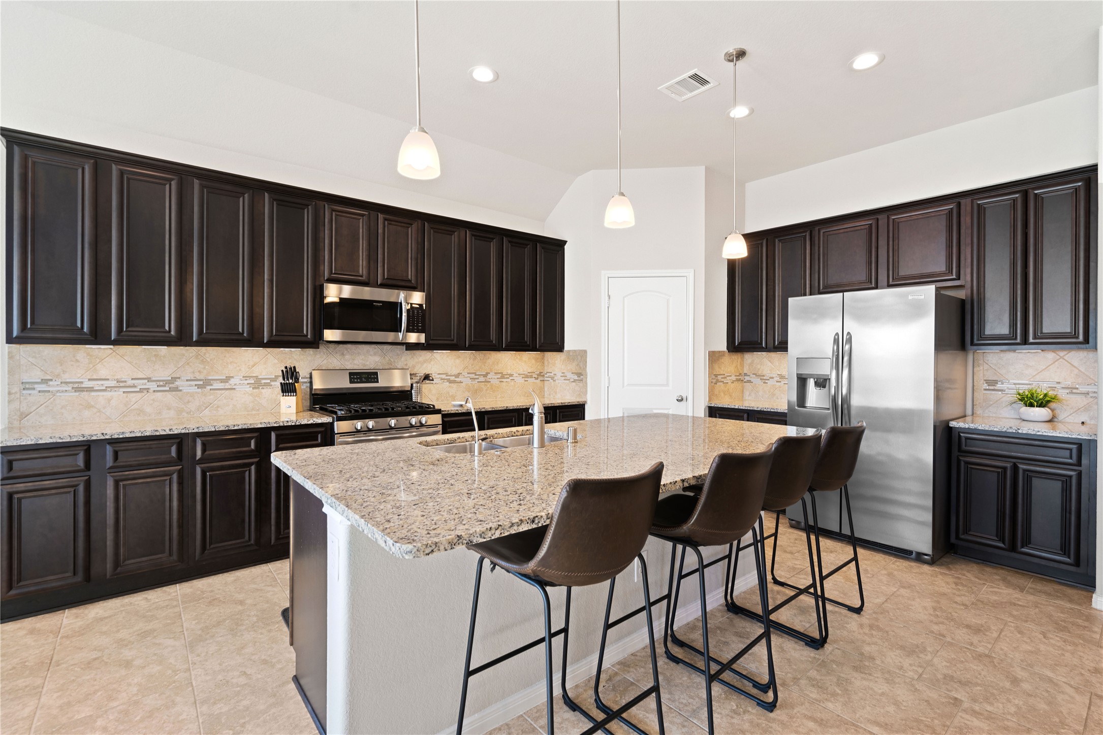 14300 Congaree Court Conroe, TX 77384 - Photo 13 of 31 a kitchen with granite countertop a refrigerator stove microwave and cabinets