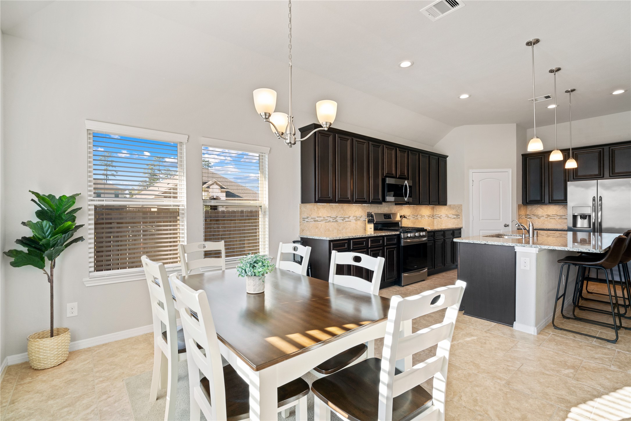 14300 Congaree Court Conroe, TX 77384 - Photo 15 of 31 a kitchen with granite countertop kitchen island a table and chairs in it