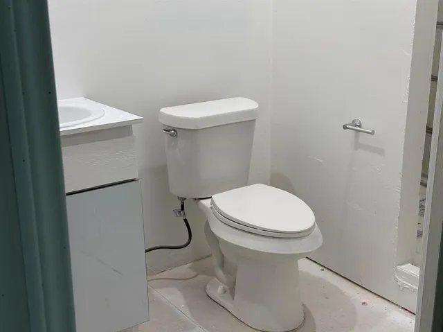 a white toilet sitting next to a white sink and vanity