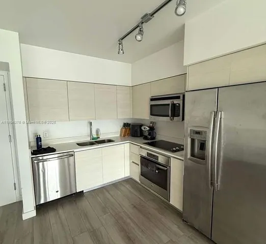 a kitchen with stainless steel appliances a sink dishwasher a refrigerator and a stove top oven