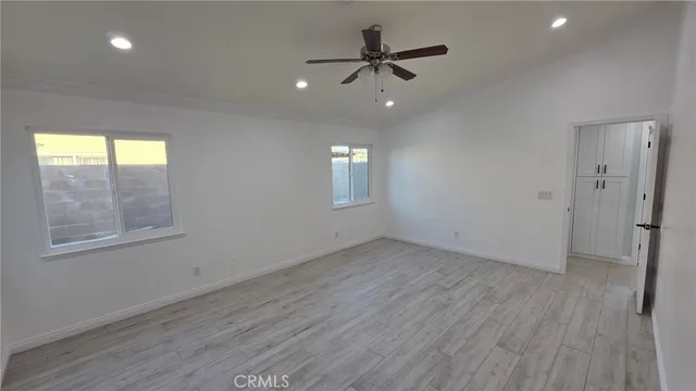 an empty room with wooden floor fan and windows