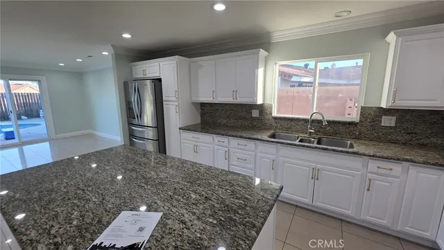 a kitchen with granite countertop a sink a refrigerator and window