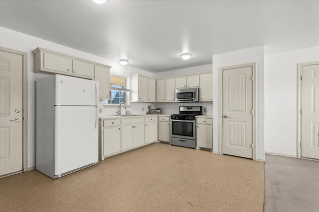 a kitchen with white cabinets and white stainless steel appliances