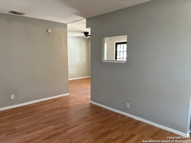 a view of an empty room with wooden floor and a window