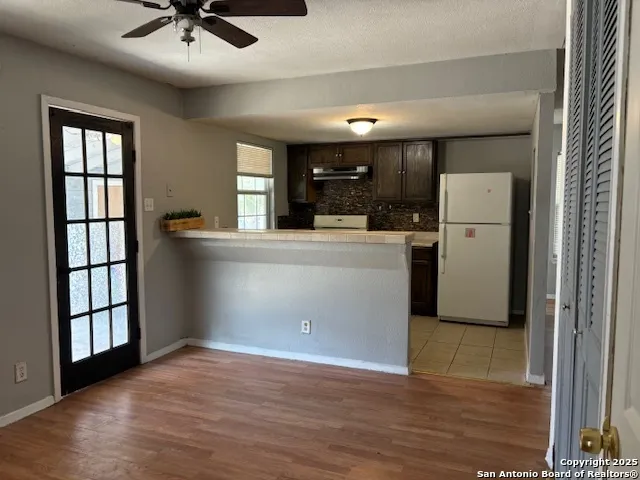 a view of a kitchen with a sink wooden cabinet and a refrigerator