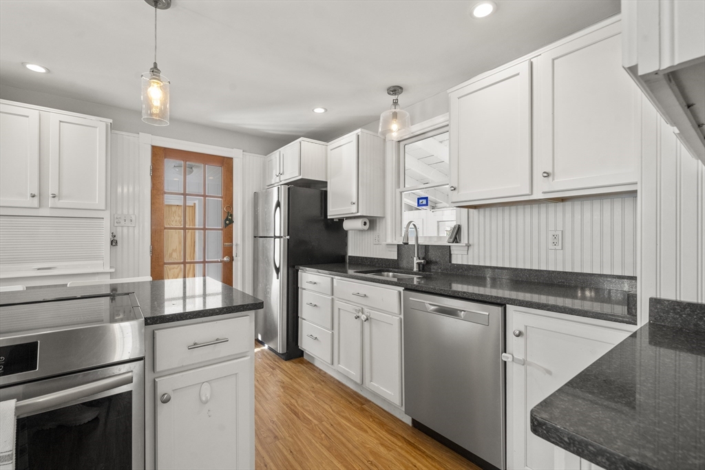 446 Ralph Talbot Street Weymouth, MA 02190 - Photo 10 of 28 a kitchen with granite countertop white cabinets and stainless steel appliances