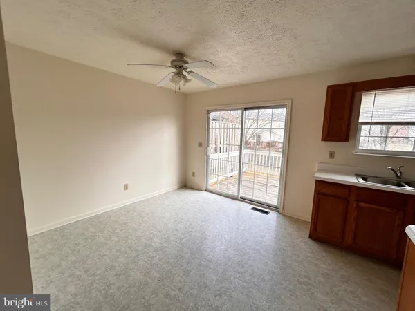 a view of an empty room with a window and a kitchen