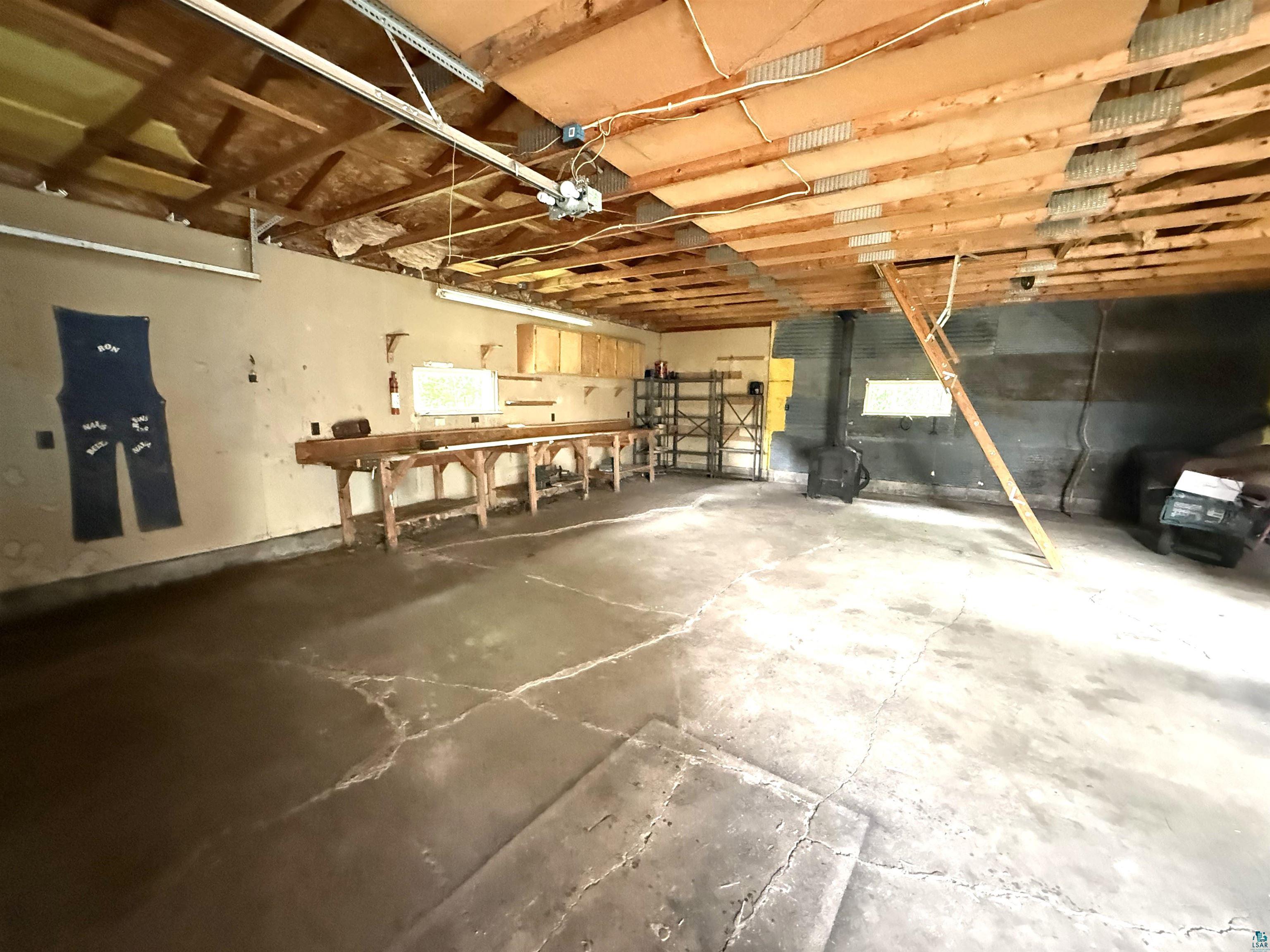 3541 Bent Trout Lake Road Barnum, MN 55707 - Photo 34 of 41 Spacious utility area featuring exposed wood beam ceiling, concrete flooring, and a lengthy built-in workbench