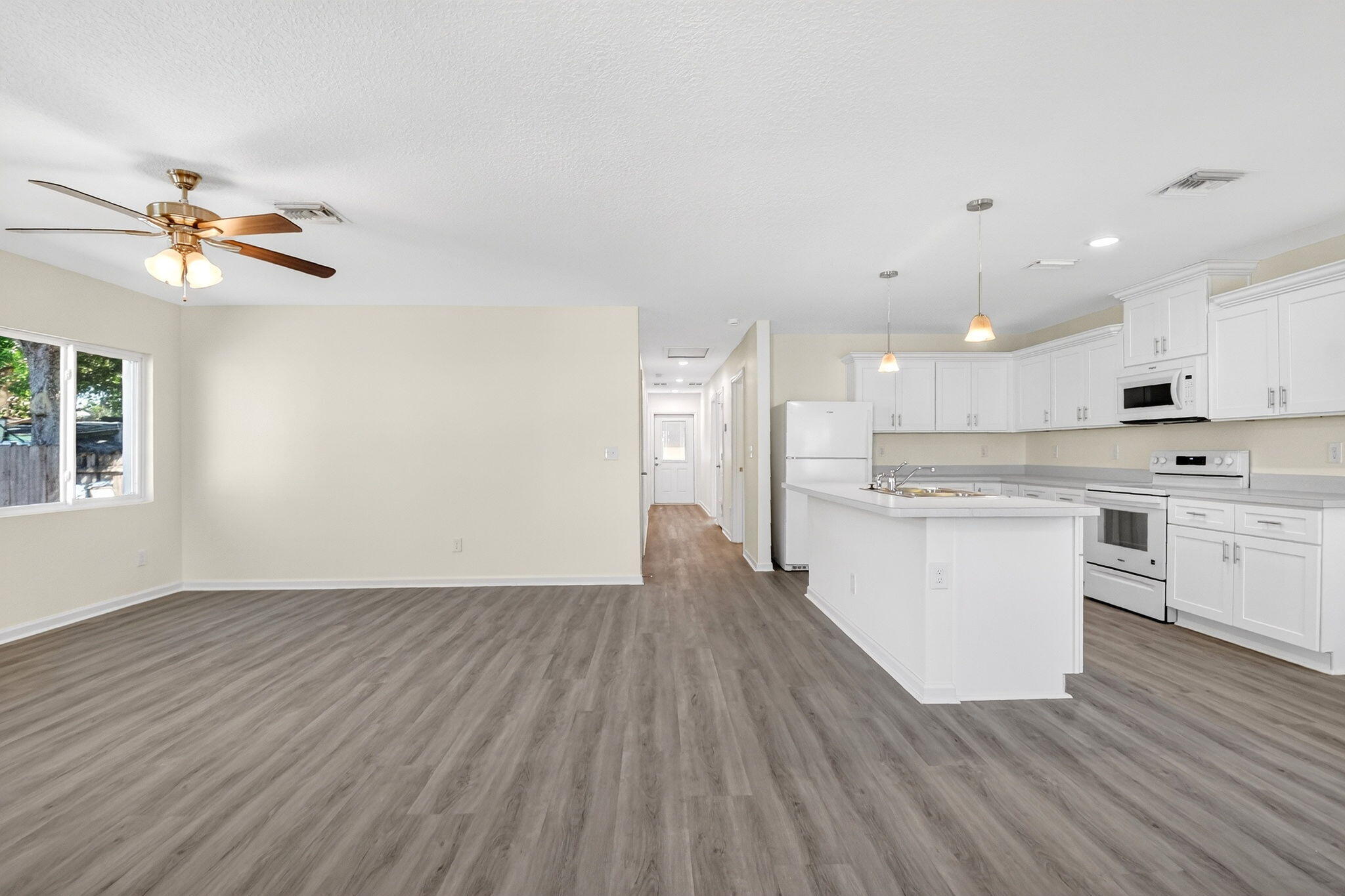 a view of kitchen with granite countertop white cabinets a sink oven and a dishwasher with wooden floor