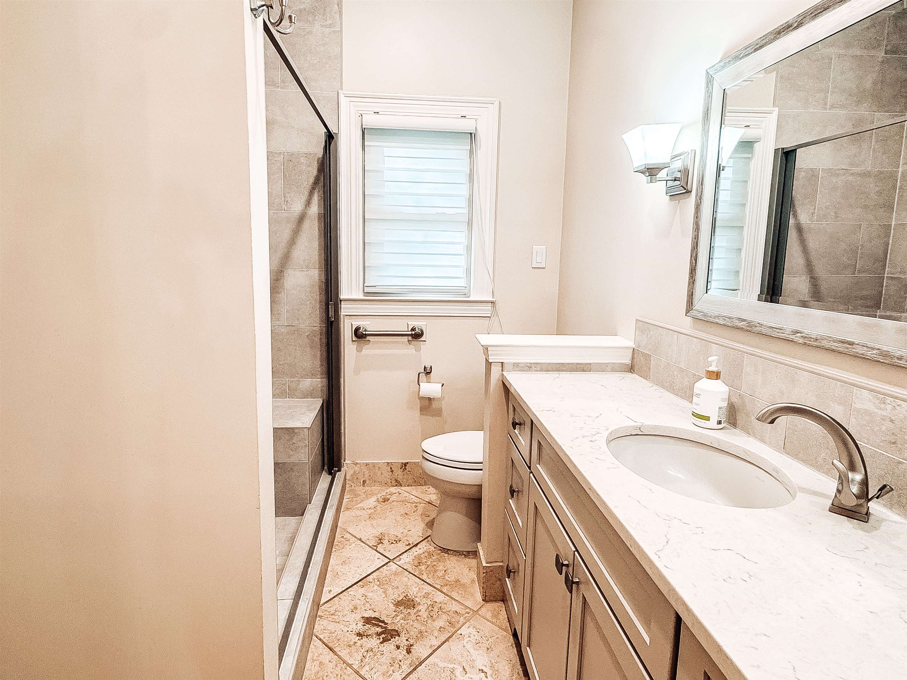 832 South Tree Drive Collierville, TN 38017 - Photo 20 of 40 Bathroom featuring a glass-enclosed shower with a built-in bench, a single vanity with an integrated sink and light-colored countertop, decorative wall sconces, a framed mirror, and tile flooring