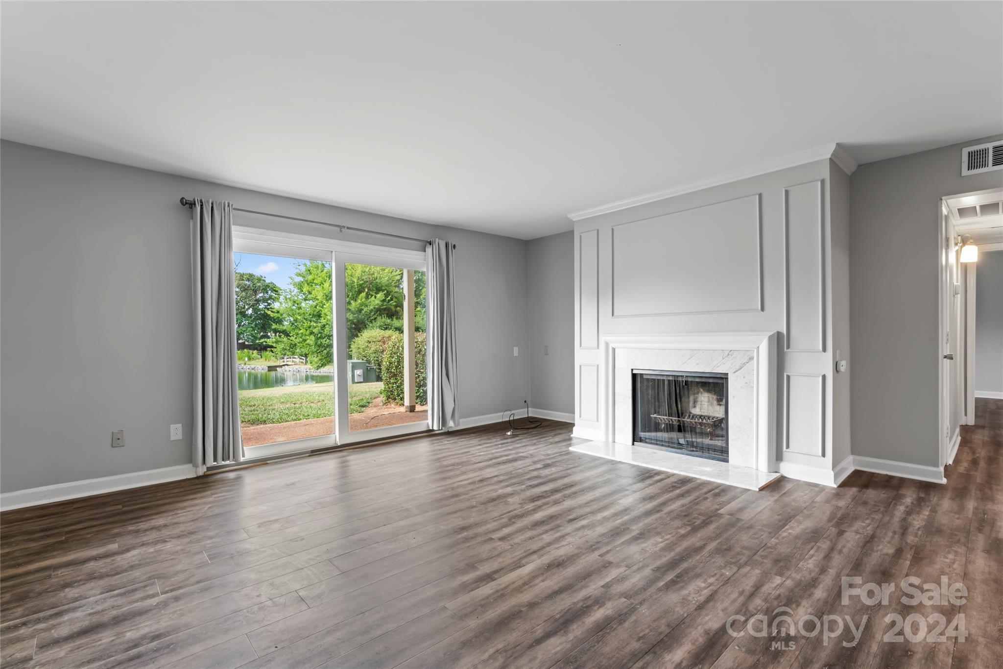 7035 Quail Hill Road Charlotte, NC 28210 - Photo 6 of 40 an empty room with wooden floor fireplace and windows