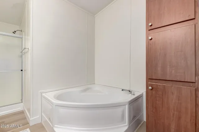 a view of an empty room with wooden floor and a ceiling fan
