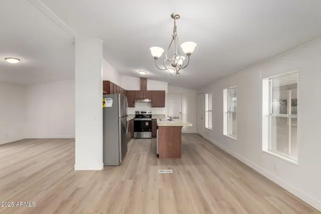 a kitchen with a sink a refrigerator a stove and white cabinets with wooden floor