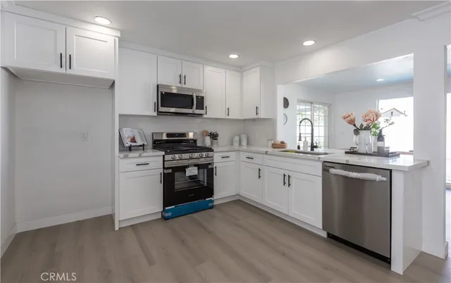 a kitchen with granite countertop white cabinets and stainless steel appliances