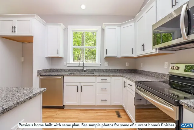 a kitchen with stainless steel appliances granite countertop a stove a sink and a white cabinets