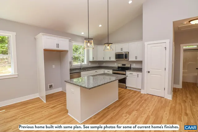 a kitchen with stainless steel appliances granite countertop a sink a stove a refrigerator and white cabinets with wooden floor