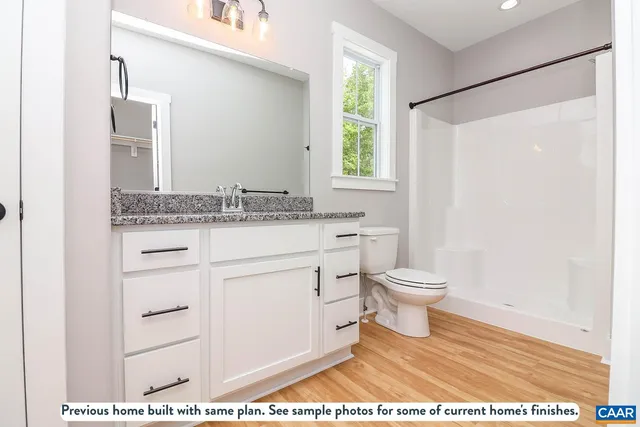 a bathroom with a granite countertop sink a toilet a mirror and a window