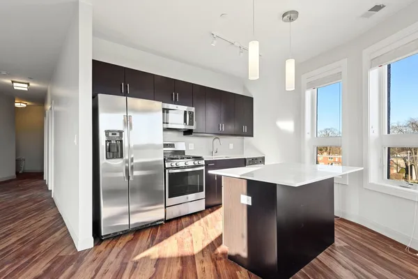 a kitchen with stainless steel appliances a sink a stove a refrigerator cabinets and a dining table