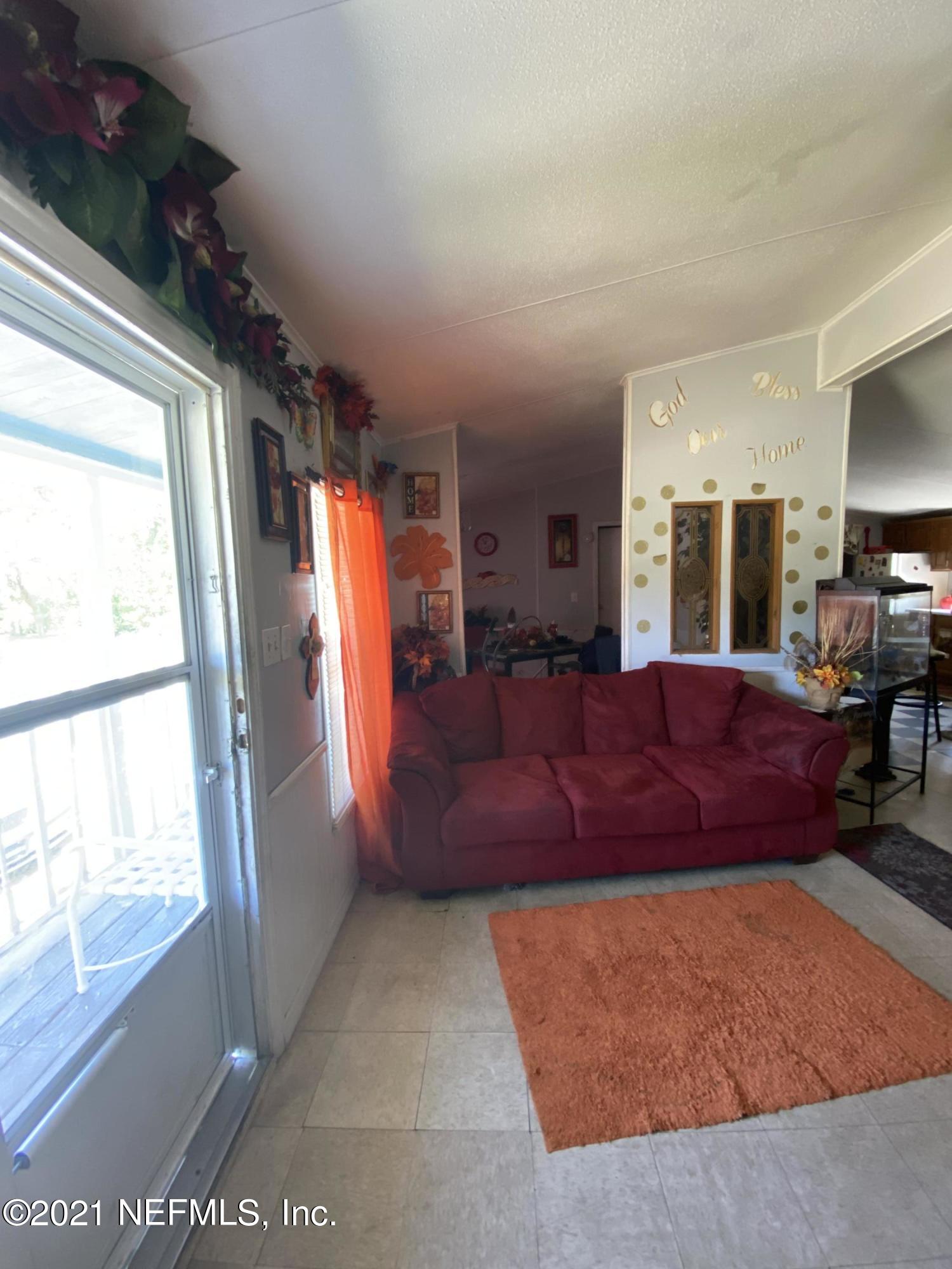 6427 Firestone Road Jacksonville, FL 32244 - Photo 33 of 55 a living room with furniture a flat screen tv and a large window