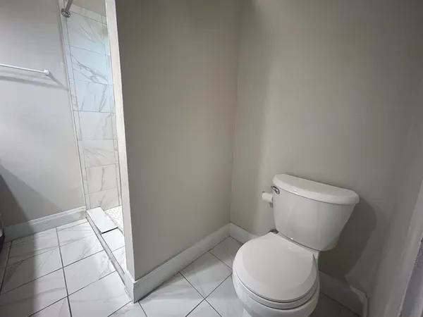 a white toilet sitting next to a shower