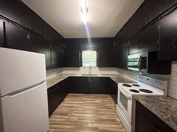 a kitchen with granite countertop stainless steel appliances a sink stove top oven and cabinets
