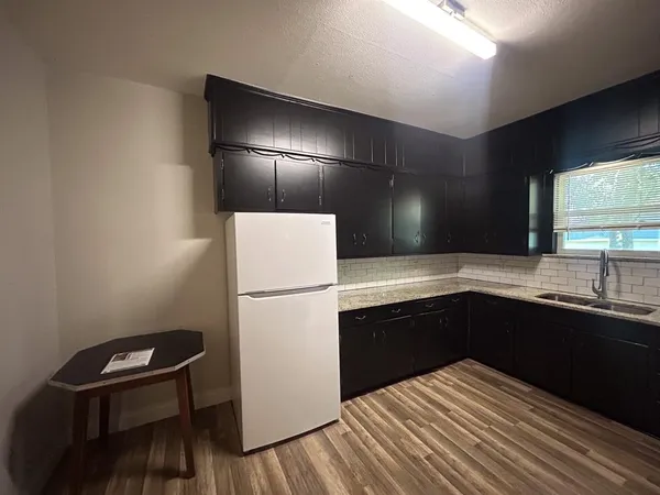 a kitchen with a sink a refrigerator and wooden floor