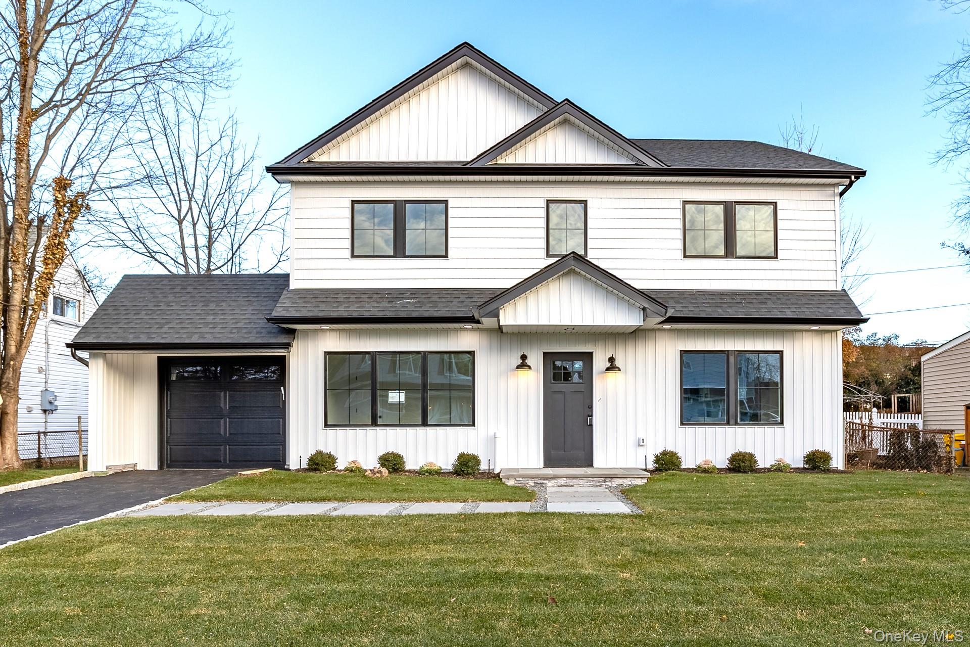 Modern farmhouse with roof with shingles, a front yard, and board and batten siding